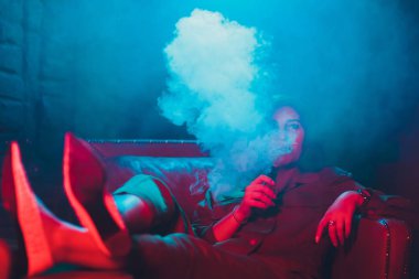 kadın odada yatakta yatan bir e-sigara içiyor. Sigara içenler kavramı Vaping.