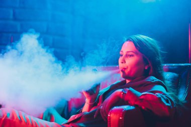 kadın odada yatakta yatan bir e-sigara içiyor. Sigara içenler kavramı Vaping.