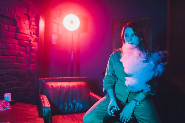 Mujer fuma un cigarrillo electrónico acostado en la cama en la habitación. Concepto de fumadores Vaping . — Foto de Stock