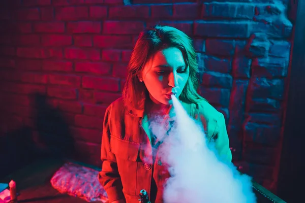 woman smokes a e-cigarette lying on the bed in the room. Smokers concept Vaping.