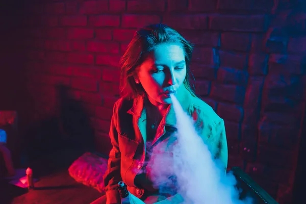 woman smokes a e-cigarette lying on the bed in the room. Smokers concept Vaping.