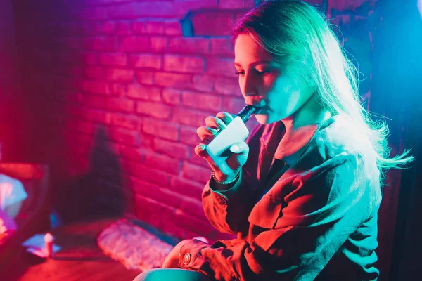 kadın odada yatakta yatan bir e-sigara içiyor. Sigara içenler kavramı Vaping.