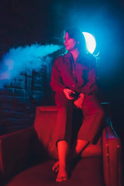 Mujer fuma un cigarrillo electrónico acostado en la cama en la habitación. Concepto de fumadores Vaping . — Foto de Stock