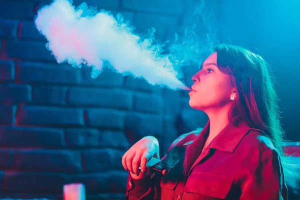 woman smokes a e-cigarette lying on the bed in the room. Smokers concept Vaping.