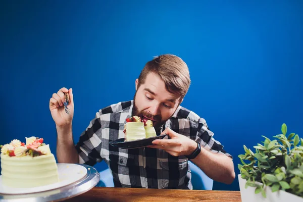 İnsanlar, eğlence, gıda kavramı - beyaz gömlek yakışıklı gülümseyen adam masada kahvaltı yeme oturuyor. Sabah kahvaltısı - sakallı adam lezzetli pasta yeme, masada fincan kapuçino veya kahve veya çay sahip.