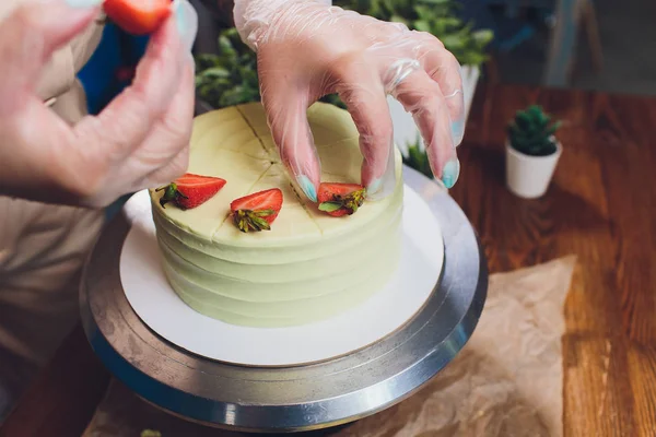 Pastelero decorado con bayas un pastel de galletas con crema blanca. La torta está sobre una mesa de madera. El concepto de pastelería casera, pasteles de cocina . — Foto de Stock