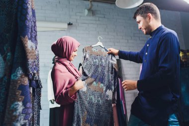 Gülümseyen genç müslüman çift alışveriş ve bir tekstil mağazasında halı bakıyor.