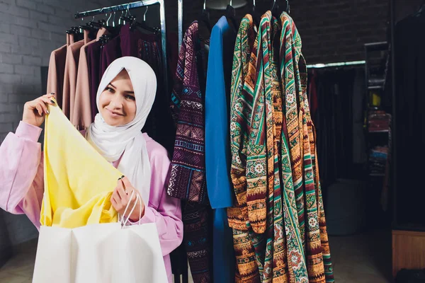 Arab woman in traditional Muslim clothes buys a new dress in an Oriental store.