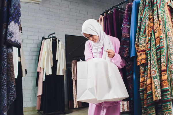 Arab woman in traditional Muslim clothes buys a new dress in an Oriental store.