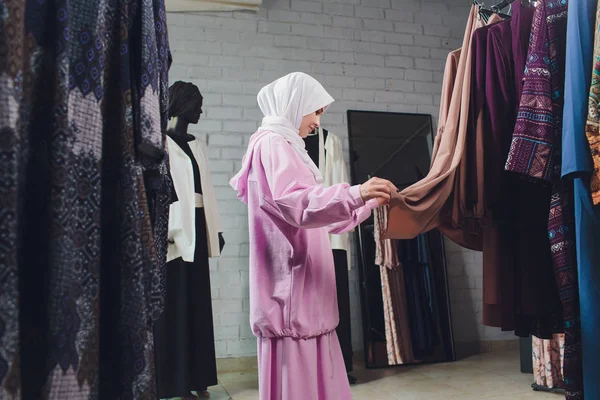 Арабская женщина в традиционной мусульманской одежде покупает новое платье в восточном магазине . — стоковое фото