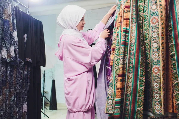 Geleneksel Müslüman giyimli Arap kadın Bir Oriental mağazasında yeni bir elbise satın alır.