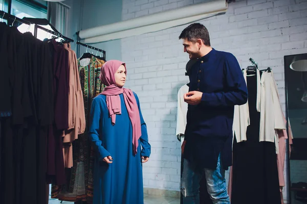 Gülümseyen genç müslüman çift alışveriş ve bir tekstil mağazasında halı bakıyor.