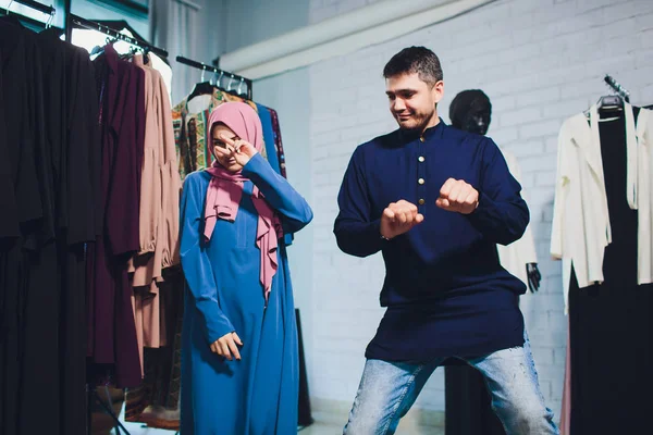 Gülümseyen genç müslüman çift alışveriş ve bir tekstil mağazasında halı bakıyor.