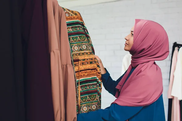 Mujer árabe vestida con ropa musulmana tradicional compra un vestido nuevo en una tienda oriental . — Foto de Stock