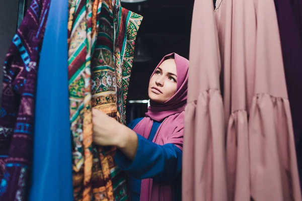 Araberin in traditioneller muslimischer Kleidung kauft ein neues Kleid in einem orientalischen Geschäft. — Stockfoto