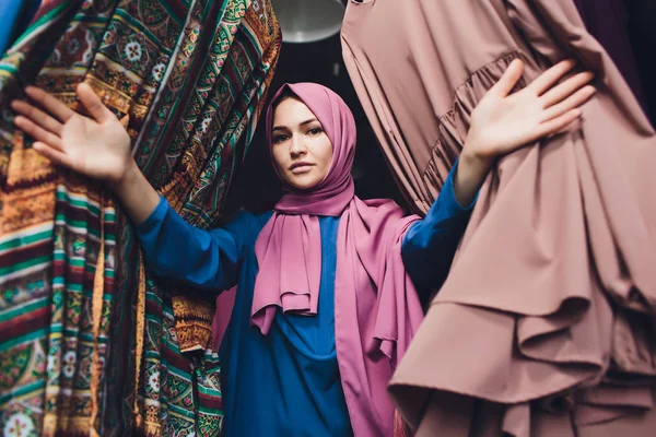 Arabische vrouw in traditionele moslim kleding koopt een nieuwe jurk in een oosterse winkel. — Stockfoto