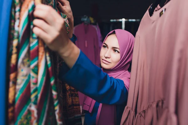 Mujer árabe vestida con ropa musulmana tradicional compra un vestido nuevo en una tienda oriental . — Foto de Stock