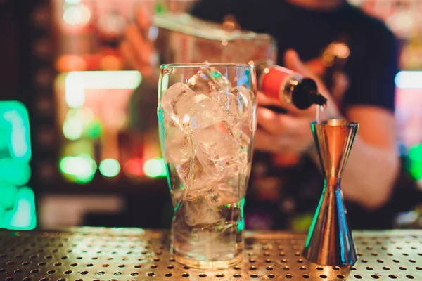 Barman espremendo suco de limão fresco em um copo usando imprensa cítrica e salpicando-o para fora fazendo um coquetel alcoólico . — Fotografia de Stock