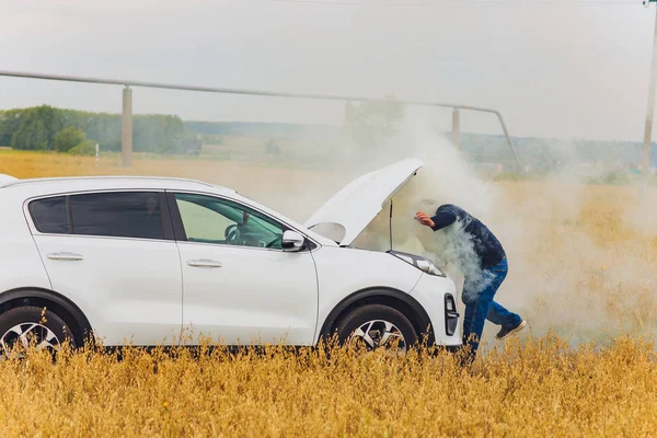 Motorista estressado e frustrado puxando o cabelo enquanto estava na estrada ao lado do carro quebrado. Problemas de viagem e conceitos de assistência. fumaça . — Fotografia de Stock