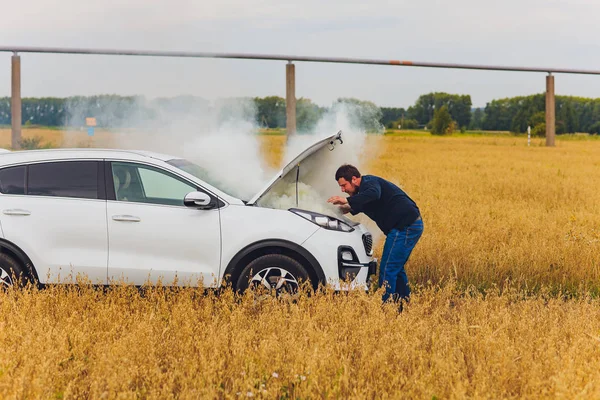 Stressad och frustrerad förare drar sitt hår medan stående på vägen bredvid trasiga bil. Road Trip problem och hjälp koncept. Rök. — Stockfoto