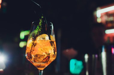 Yüksek cam, gri-gümüş arka plan, seçici odak portakal acı, meyve, buz ve soda ile Yaz kokteyl aperatif.