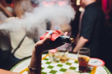 kadın odada yatakta yatan bir e-sigara içiyor. Sigara içenler kavramı Vaping.