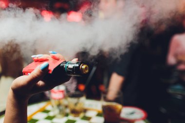 kadın odada yatakta yatan bir e-sigara içiyor. Sigara içenler kavramı Vaping.