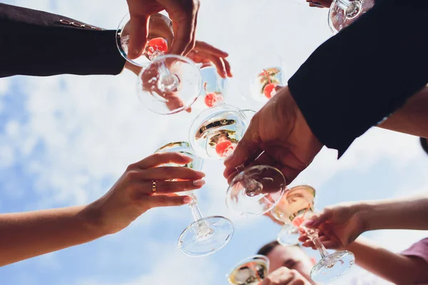 Gros plan du groupe de personnes qui claquent des verres avec du vin ou du champagne devant un fond bokeh . — Photo