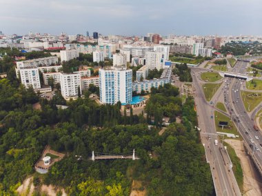 Ufa, Rusya, 1 Temmuz 2019: Beyaz Nehir, yeşil ağaçlar ve modern yüksek katlı binalar ile bir yamaç üzerinde renkli çatılar ile özel evlerin arka planda şehir merkezinde. Belsky Köprüsü, Ufa