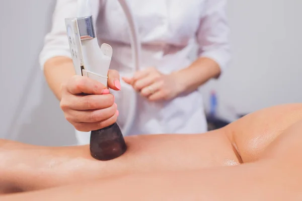 Beskuren bild av kosmetolog med rollern gör skinkor starvac massage. — Stockfoto