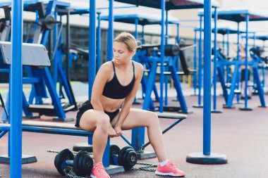 Bazı tricep dips bir parkta bankta yapıyor bir kadın atlet profil görünümü.