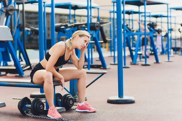 Vue de profil d'une athlète féminine faisant quelques plongées triceps sur un banc de parc . — Photo