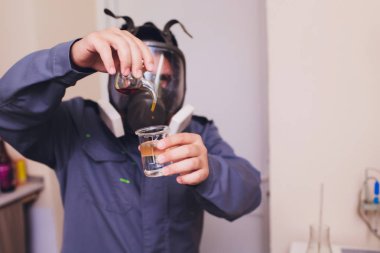 Beyaz koruyucu giysili teknolog, yiyecek ve içecek fabrikasında çalışan saç ağı ve maskesi ile. Adam uzman içecek üretimi için şişe kontrol. hazır olup luğunu kontrol etmek için iyot kullanımı