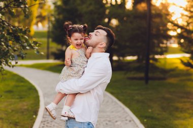 Babalık, aile ve eğlence kavramı - baba parkta kollarında küçük kızı tutarak.