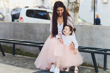 mutlu anneler ve kızları bir şehirde Park bir bankta oturmuş.