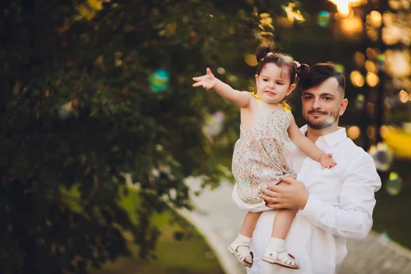 Vaderschap, familie en Leisure concept-vader Holding kleine dochter in zijn armen in Park. — Stockfoto