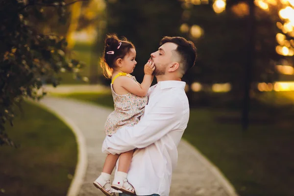 Батько тримає маленьку доньку в руках у парку . — стокове фото