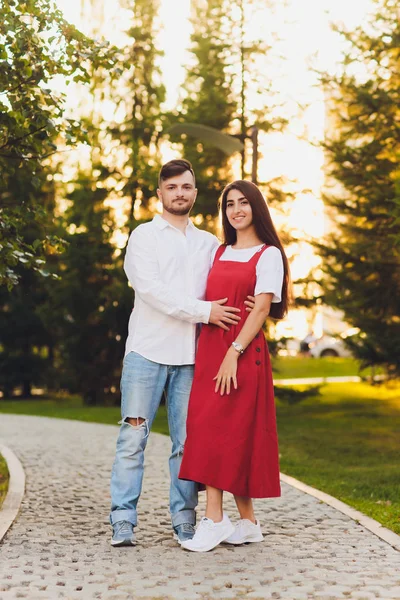 Casal feliz romântico em abraços de amor e olhar um para o outro. mulher morena atraente e seu bonito namorado barbudo no parque . — Fotografia de Stock