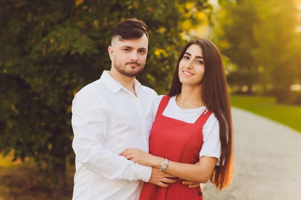 Casal feliz romântico em abraços de amor e olhar um para o outro. mulher morena atraente e seu bonito namorado barbudo no parque . — Fotografia de Stock