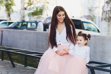 mutlu anneler ve kızları bir şehirde Park bir bankta oturmuş.