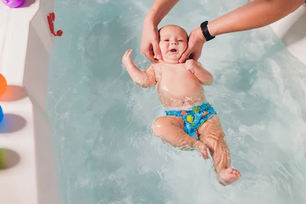 Bir baba havuzda yüzme dersleri sırasında bebek çocuk yardımcı olur. — Stok fotoğraf