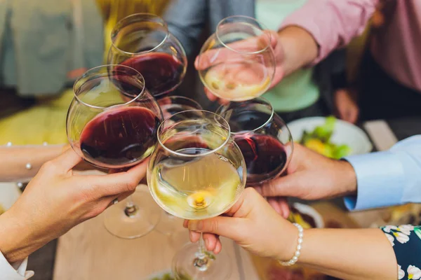 Közelkép emberek csoportjáról, akik poharakat csörömpölnek borral vagy pezsgővel bokeh háttér előtt. idős emberek kezei — Stock Fotó