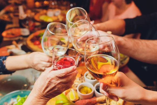 Nahaufnahme einer Gruppe von Menschen, die vor Bokeh-Hintergrund Gläser mit Wein oder Champagner klappern. Ältere Hände — Stockfoto