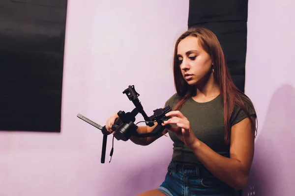 Een jonge vrouw gebruikt een gimbal camera stabilisator om beelden te maken in een huis. Verschillende antiek filmen met een professionele moderne spiegelreflexcamera. — Stockfoto