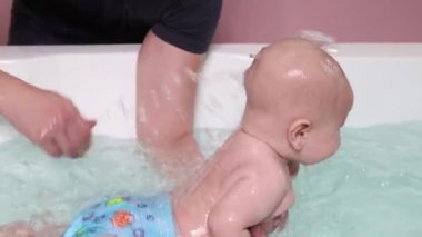 Bir baba havuzda yüzme dersleri sırasında bebek çocuk yardımcı olur.