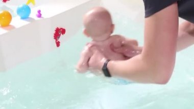 Bir baba havuzda yüzme dersleri sırasında bebek çocuk yardımcı olur.