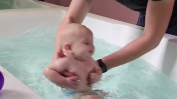 Um pai ajuda é menino durante as aulas de natação na piscina . — Vídeo de Stock