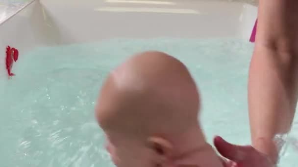 Un padre ayuda es niño durante las clases de natación en la piscina . — Vídeo de stock