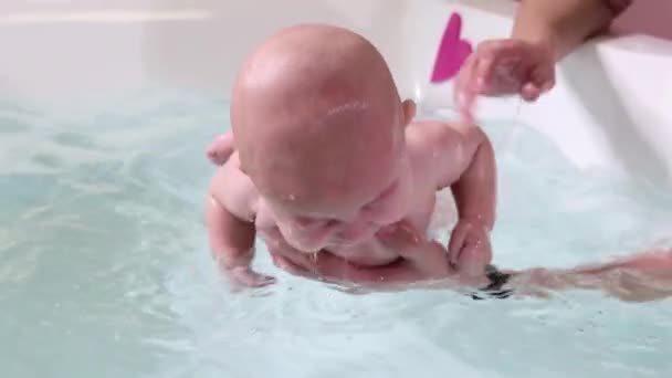 Ojciec pomaga niemowlaka podczas lekcji pływania w basenie. — Wideo stockowe