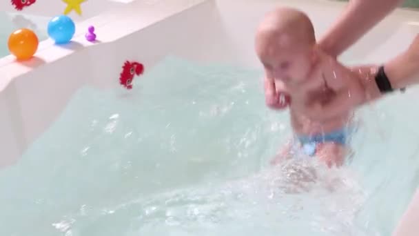 Un padre aiuta è bambino durante le lezioni di nuoto in piscina . — Video Stock